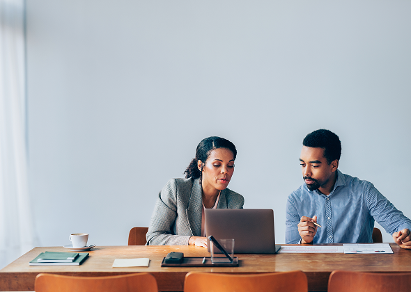 Two colleagues reviewing information together on a laptop