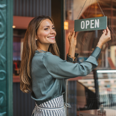 Small business owner hanging an Open sign on a storefront door